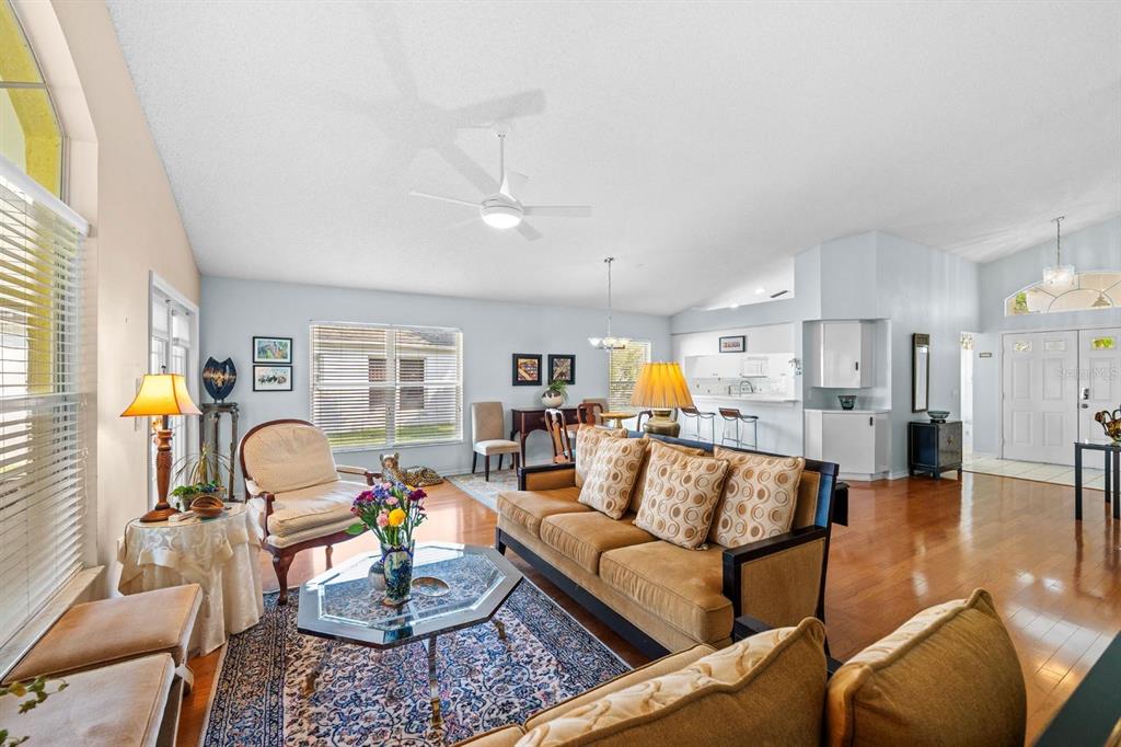 A living room with hardwood floors, a brown sofa, a coffee table, and a ceiling fan — 1249 WINDING WILLOW DRIVE, TRINITY, FL