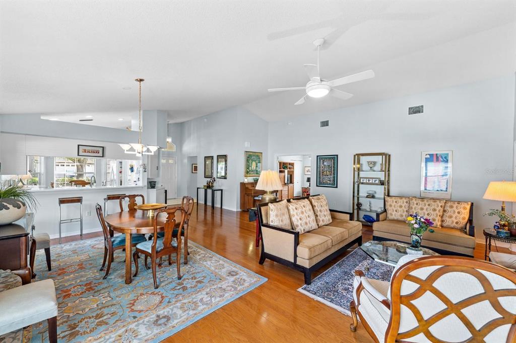 A spacious living and dining area with hardwood floors, vaulted ceilings, and neutral walls — 1249 WINDING WILLOW DRIVE, TRINITY, FL