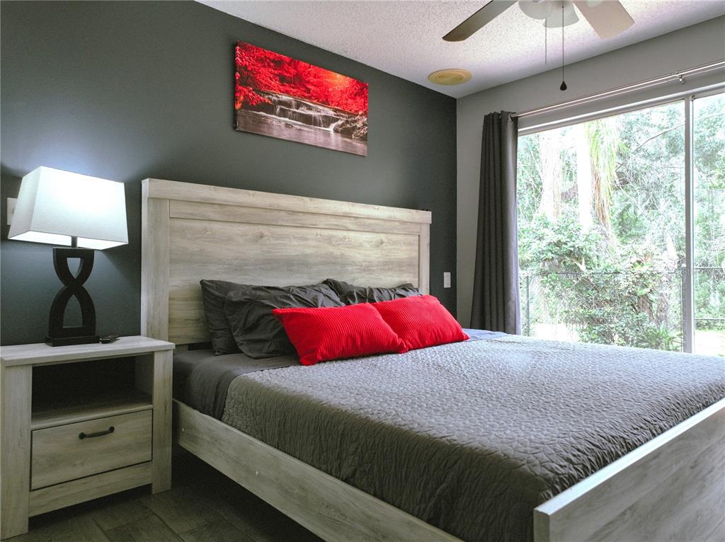A bedroom features a light wood bed frame, dark gray walls, and a red landscape painting — 111 OAK LEE DRIVE, LUTZ, FL