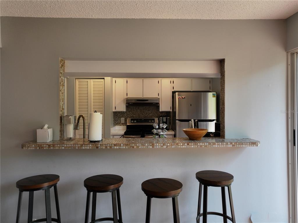 A kitchen pass-through window with a mosaic tile bar overlooks a kitchen with white cabinets — 111 OAK LEE DRIVE, LUTZ, FL