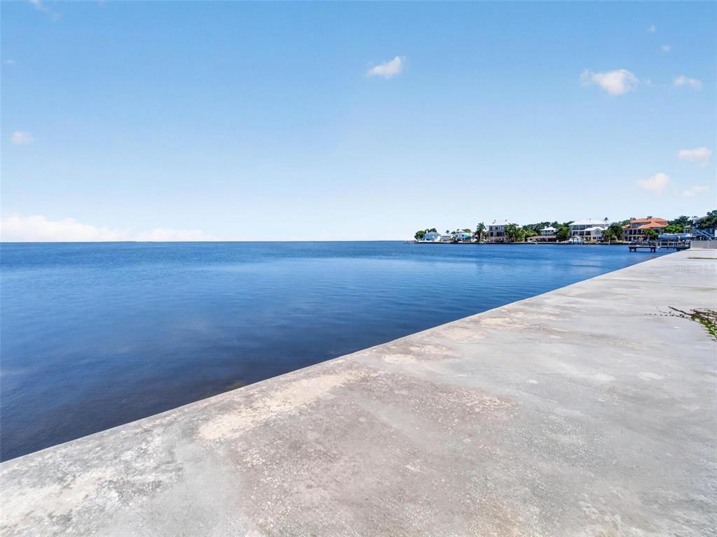 A concrete seawall borders a calm body of water under a clear blue sky — 621 N MAYO STREET, CRYSTAL BEACH, FL