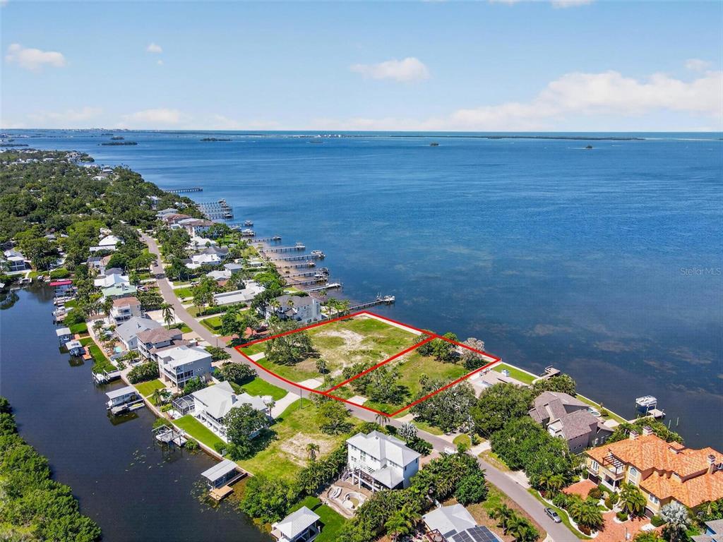 An aerial view shows two adjacent waterfront vacant lots outlined in red along a bay — 621 N MAYO STREET, CRYSTAL BEACH, FL