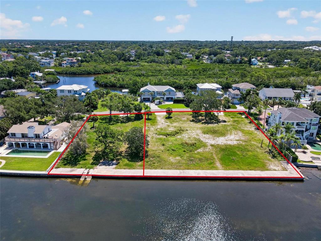 An aerial view shows two adjacent waterfront vacant lots outlined in red along a canal — 621 N MAYO STREET, CRYSTAL BEACH, FL
