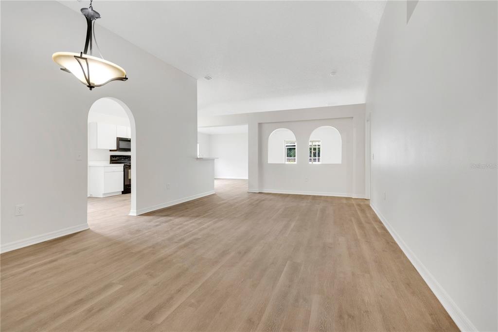 An empty living area features white walls, light wood-look flooring, and two arched wall cutouts — 6203 VENEZIA PLACE, RIVERVIEW, FL
