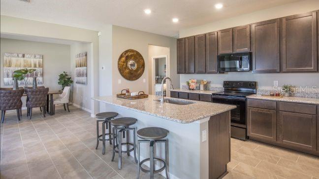 A kitchen with dark wood cabinets, granite countertops, and a central island with bar stools — 1927 TRAVELERS PALM DRIVE, EDGEWATER, FL