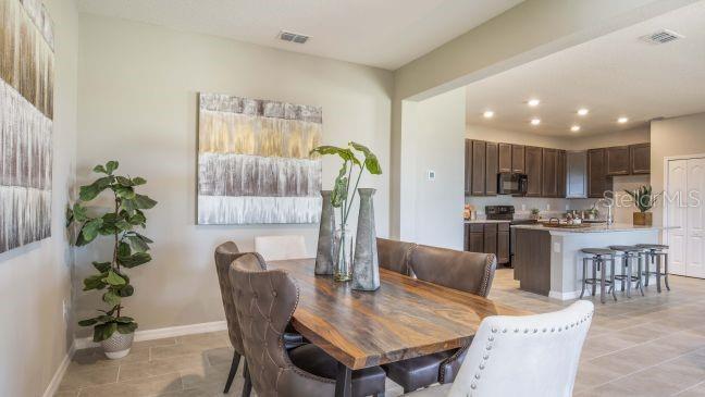 A dining area with a wooden table and chairs sits adjacent to an open kitchen — 1927 TRAVELERS PALM DRIVE, EDGEWATER, FL