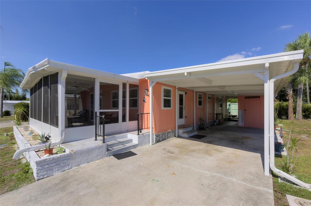 A peach-colored mobile home with a screened-in porch, a concrete driveway, and a carport — 24437 HARBORVIEW ROAD UNIT 5, PUNTA GORDA, FL