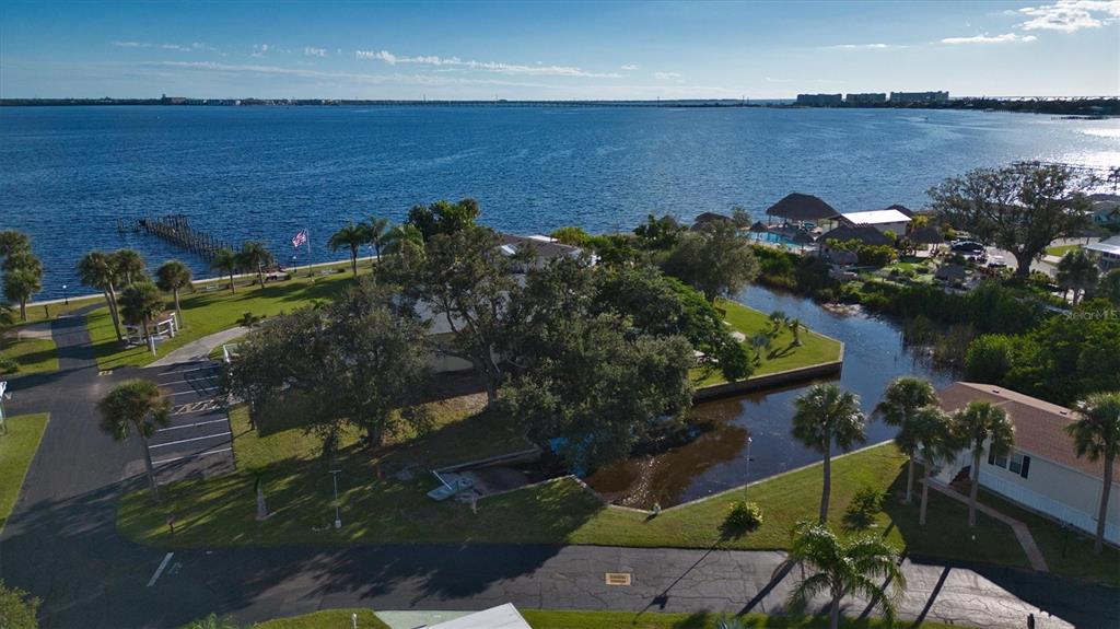 An aerial view shows a waterfront property with a canal, trees, and a boat dock — 24437 HARBORVIEW ROAD UNIT 5, PUNTA GORDA, FL