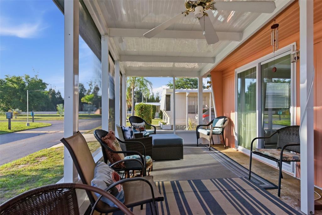 A screened-in porch features wicker chairs, a striped rug, and a ceiling fan — 24437 HARBORVIEW ROAD UNIT 5, PUNTA GORDA, FL