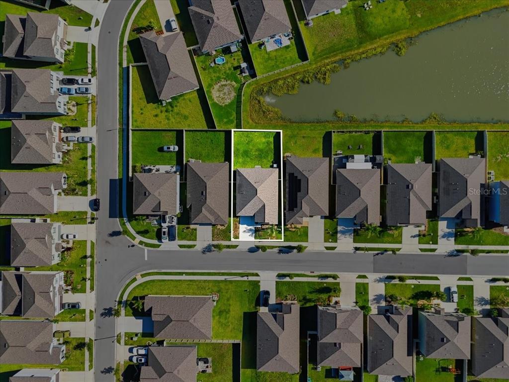 The backyard of a single-story house features a grassy lawn and a white vinyl fence — 4316 TROTTERS WAY, LAKELAND, FL