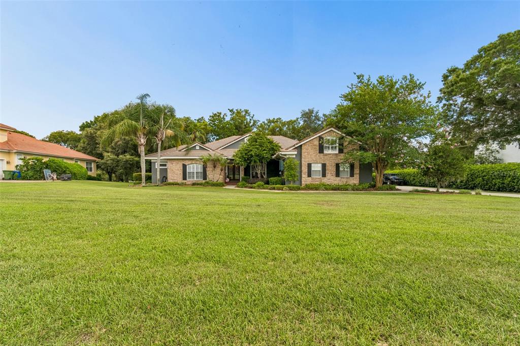 A single-story brick house with a tiled roof sits on a large grassy lawn — 12716 TRADITION DRIVE, DADE CITY, FL