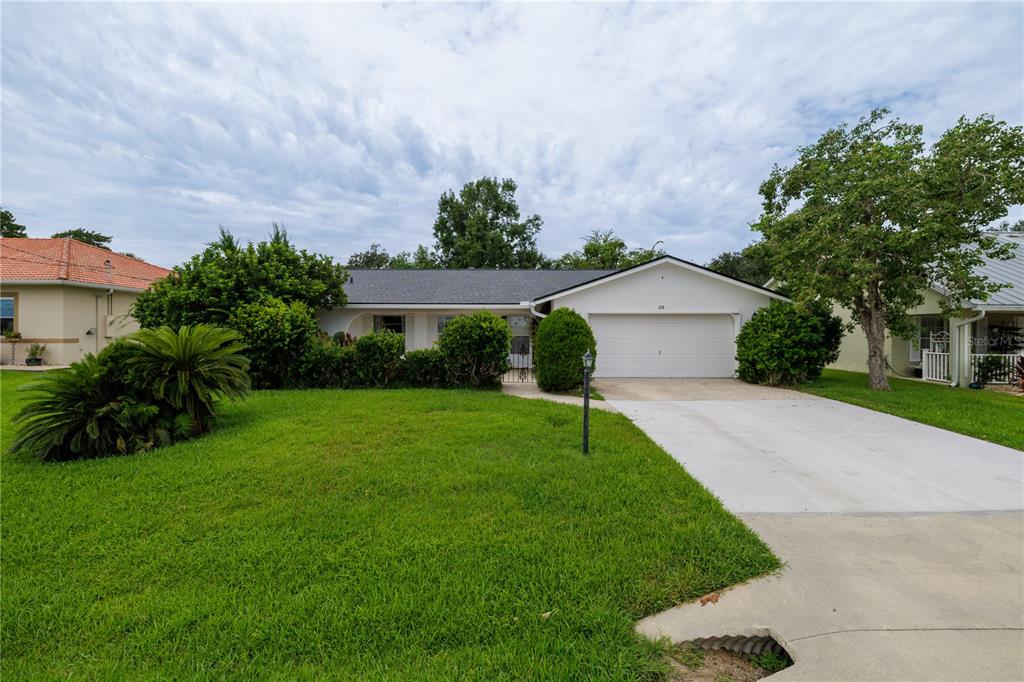 A single-story house with a white exterior, a two-car garage, and a large front lawn — 28 FLEMING COURT, PALM COAST, FL