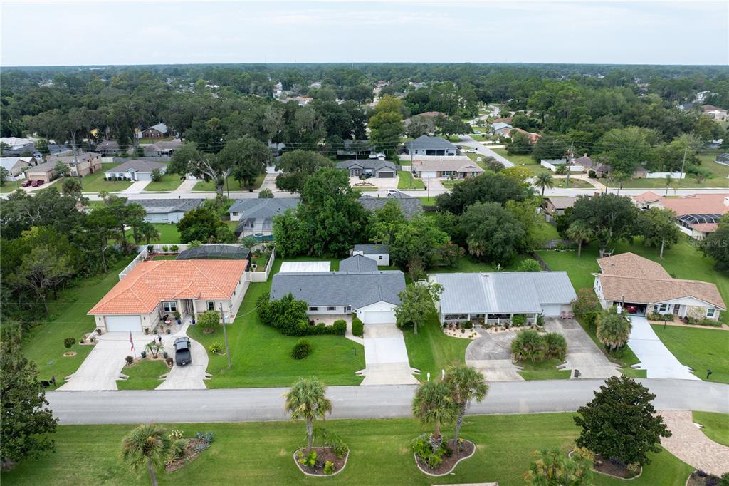 An aerial view shows several suburban houses with driveways, lawns, and trees in a neighborhood — 28 FLEMING COURT, PALM COAST, FL