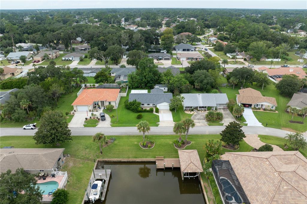 An aerial view shows suburban houses, a canal with a boat dock, and green lawns — 28 FLEMING COURT, PALM COAST, FL