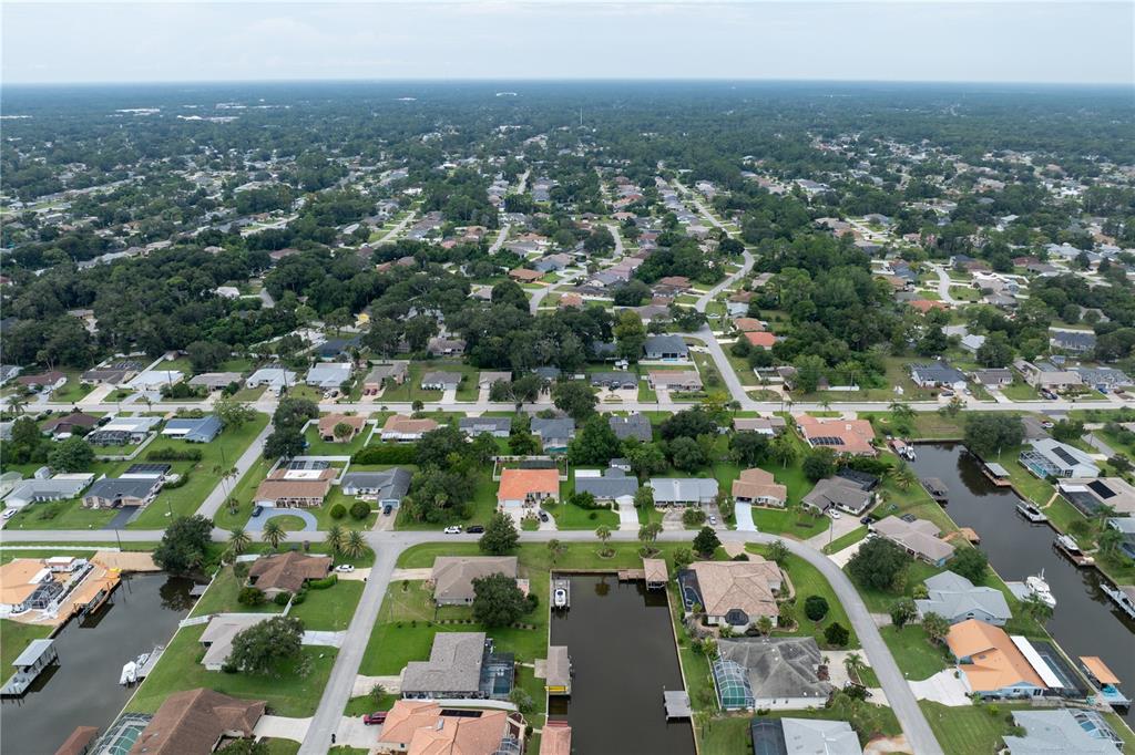An aerial view shows a suburban neighborhood with houses, streets, and a canal — 28 FLEMING COURT, PALM COAST, FL