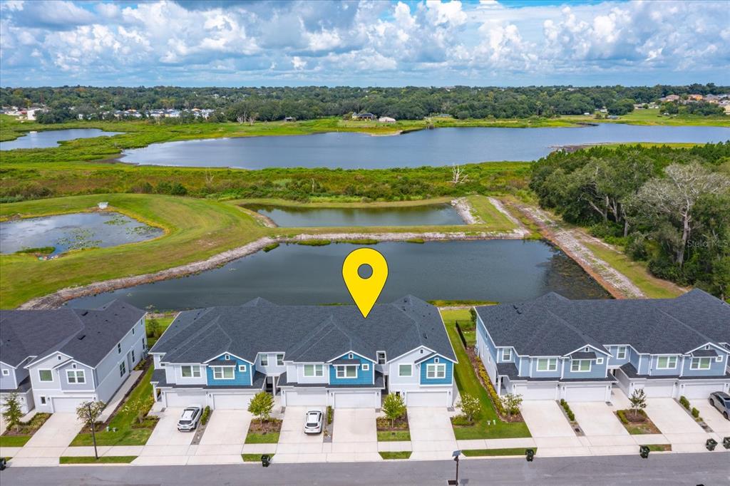 An aerial view shows a row of townhouses situated in front of a large pond — 1914 TERRAPIN ROAD, OCOEE, FL