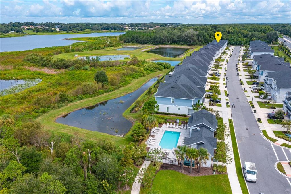 An aerial view shows a row of townhomes next to a swimming pool and lake — 1914 TERRAPIN ROAD, OCOEE, FL