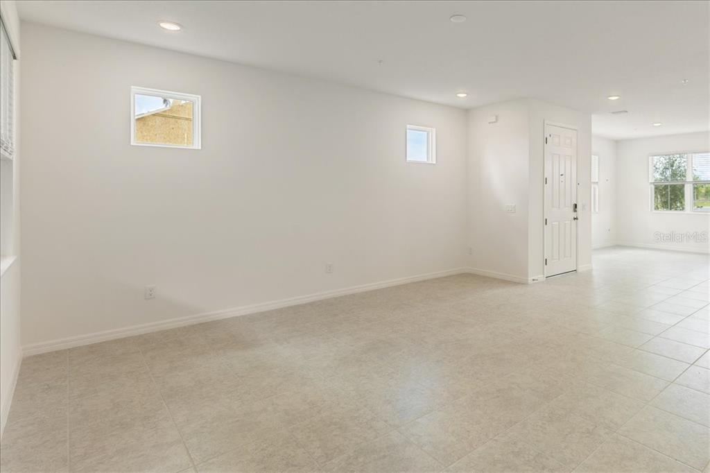 An empty room with white walls, tile flooring, recessed lighting, and a white entry door — 1552 SILVER LINING WAY, APOPKA, FL