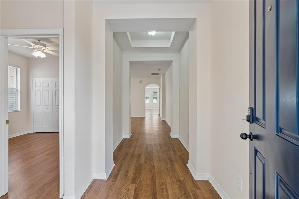 A view from an entryway looking down a hallway with wood-look flooring and white walls — 4844 FLINT ROAD, WINDERMERE, FL