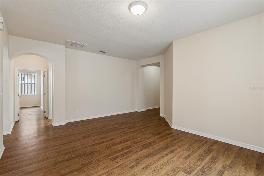 An empty room with light-colored walls, wood-look flooring, and an arched doorway — 4844 FLINT ROAD, WINDERMERE, FL
