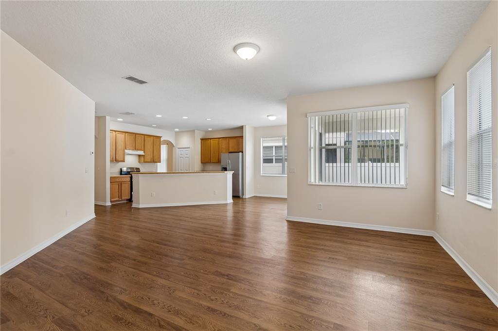An open-concept living area with wood-look flooring leads into a kitchen with light-colored cabinets — 4844 FLINT ROAD, WINDERMERE, FL
