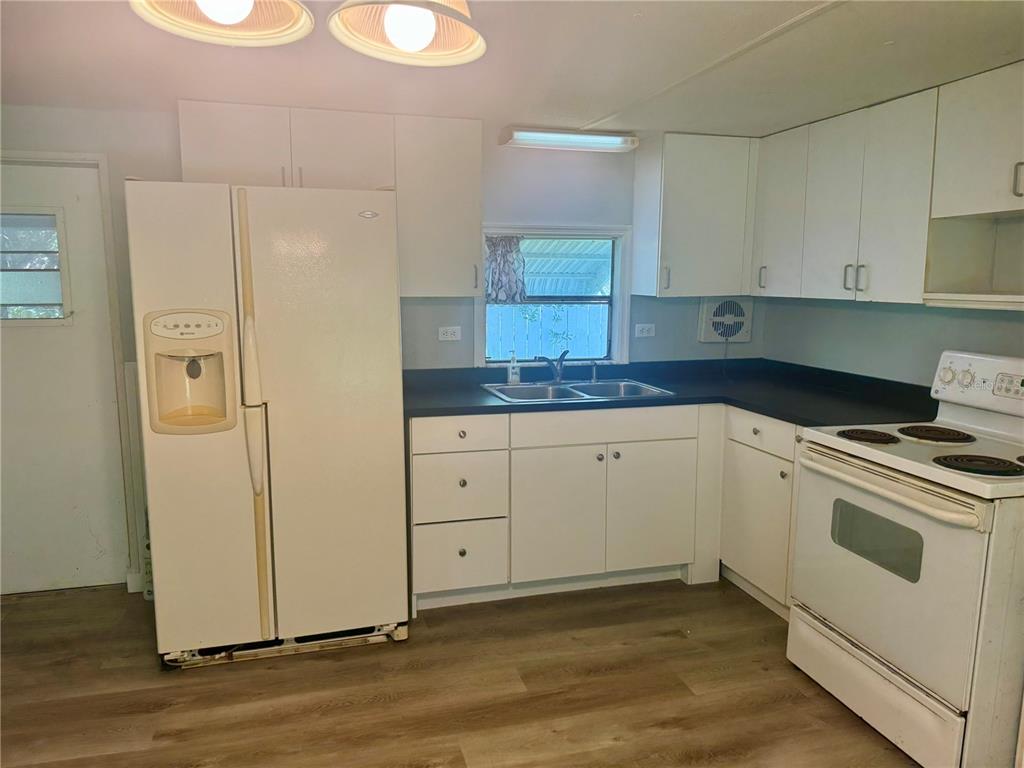 A kitchen with white cabinets, a black countertop, a white refrigerator, and a white stove — 00 FREMONT LANE, SPRING HILL, FL