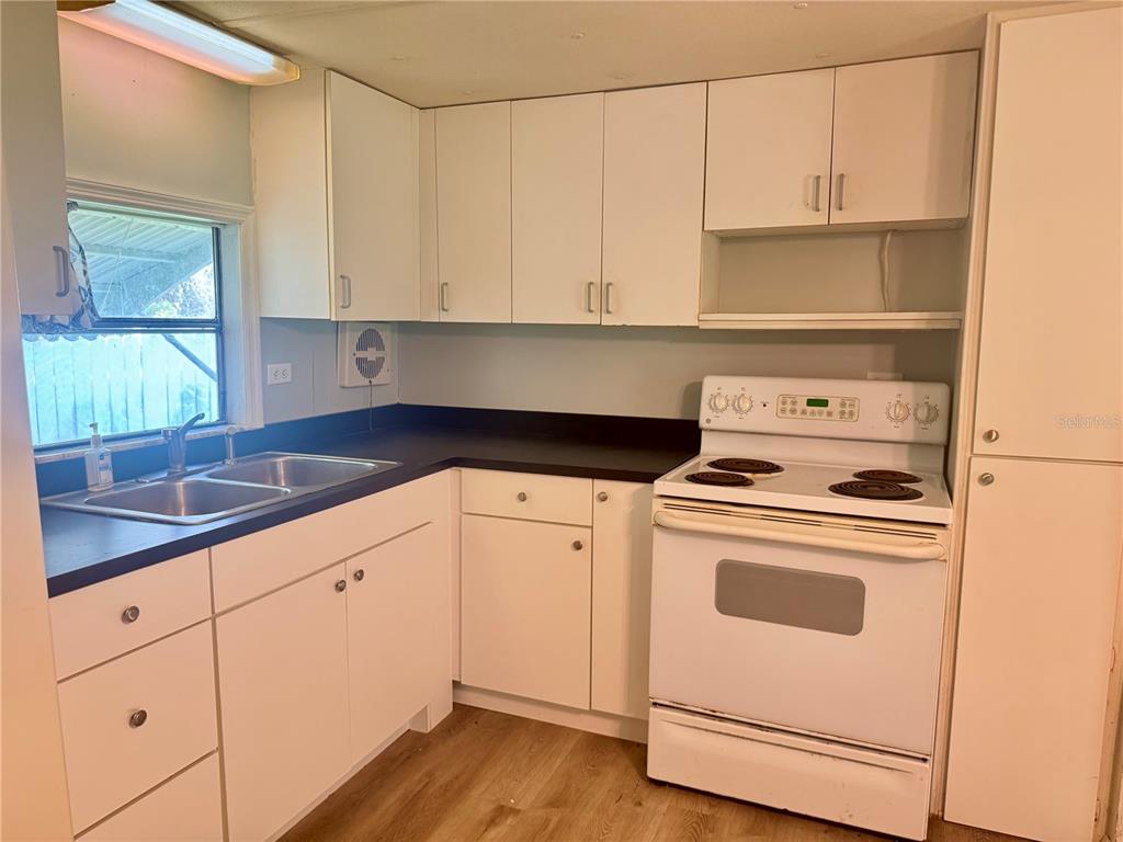 A kitchen features white cabinets, a black countertop, a double sink, and a white stove — 00 FREMONT LANE, SPRING HILL, FL