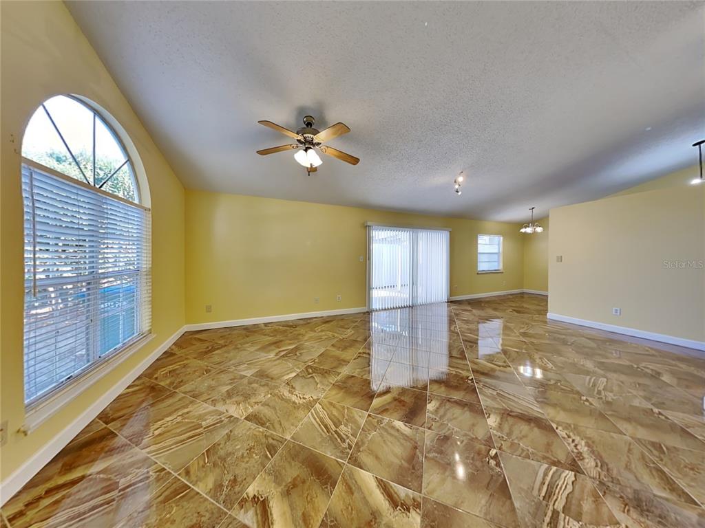 A spacious living room features yellow walls, a ceiling fan, and polished brown tile flooring — 502 SAN GABRIEL COURT, WINTER SPRINGS, FL