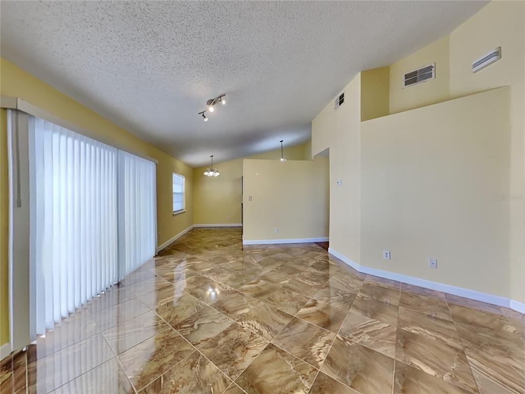An open living area features yellow walls, high ceilings, and polished brown tile flooring — 502 SAN GABRIEL COURT, WINTER SPRINGS, FL