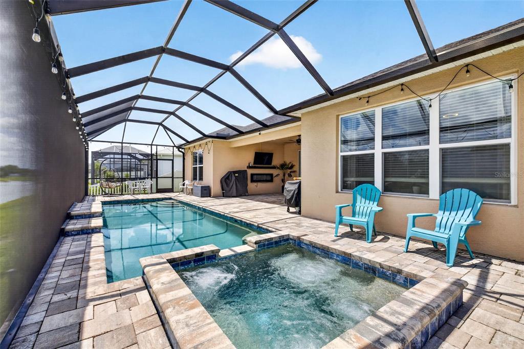 A screened-in patio features a swimming pool, a hot tub, and two blue chairs — 6946 TALAMORE DRIVE, WESLEY CHAPEL, FL