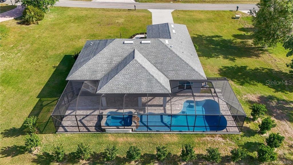 An aerial view shows a house with a screened-in pool and spa in the backyard — 594 E HARTFORD STREET, HERNANDO, FL