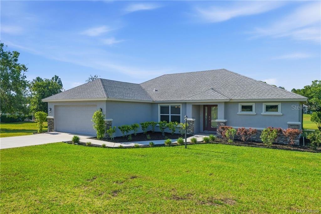 A single-story house with a gray stucco exterior, a two-car garage, and a shingled roof — 594 E HARTFORD STREET, HERNANDO, FL