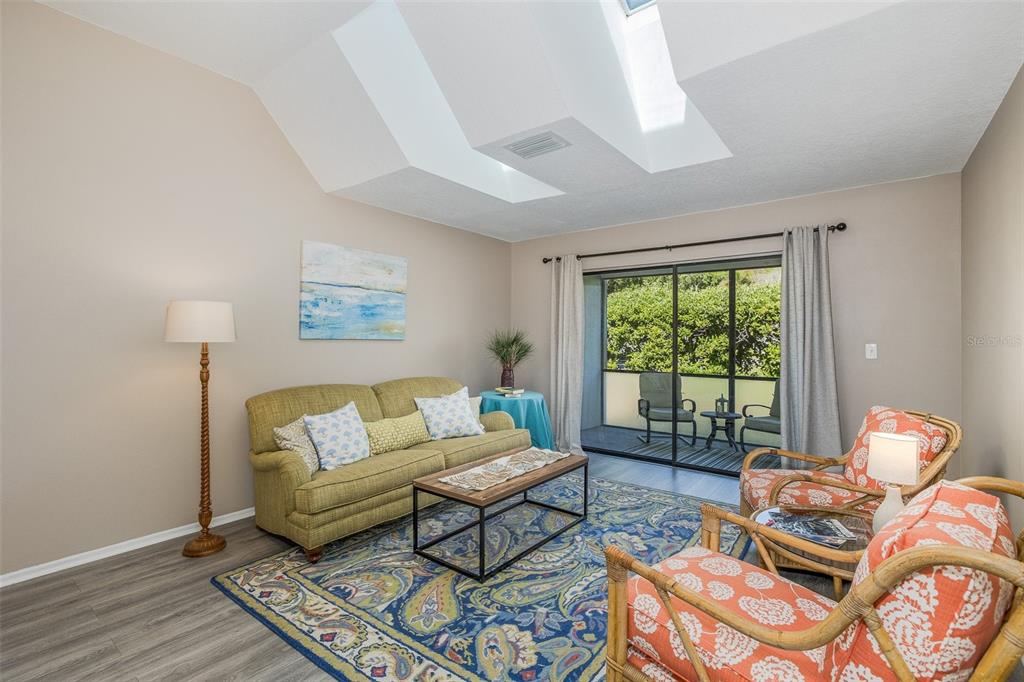 A living room with a green sofa, patterned armchairs, and an open dining area — 3843 GOLDFINCH COURT, PALM HARBOR, FL