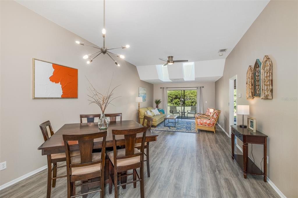 A living room features a green sofa, patterned armchairs, a rug, and a vaulted ceiling — 3843 GOLDFINCH COURT, PALM HARBOR, FL