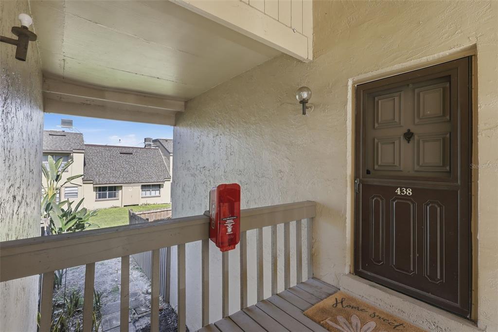 An exterior view of a residential entryway featuring a brown door, a railing, and a fire alarm — 438 WINDMEADOWS STREET UNIT 438, ALTAMONTE SPRINGS, FL