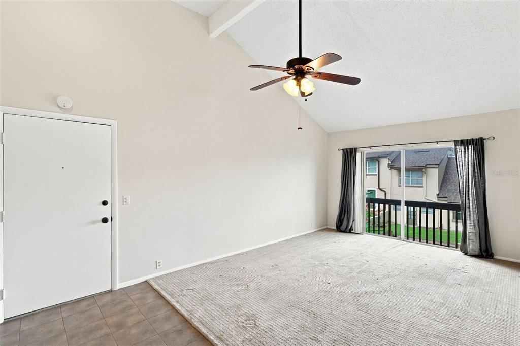 A living room features a vaulted ceiling, a ceiling fan, carpet, and a sliding glass door — 438 WINDMEADOWS STREET UNIT 438, ALTAMONTE SPRINGS, FL