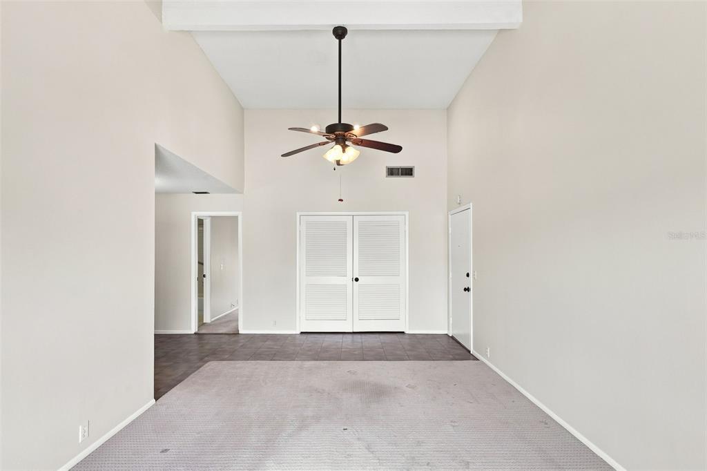 A living room with high ceilings, a ceiling fan, carpeted flooring, and white louvered doors — 438 WINDMEADOWS STREET UNIT 438, ALTAMONTE SPRINGS, FL