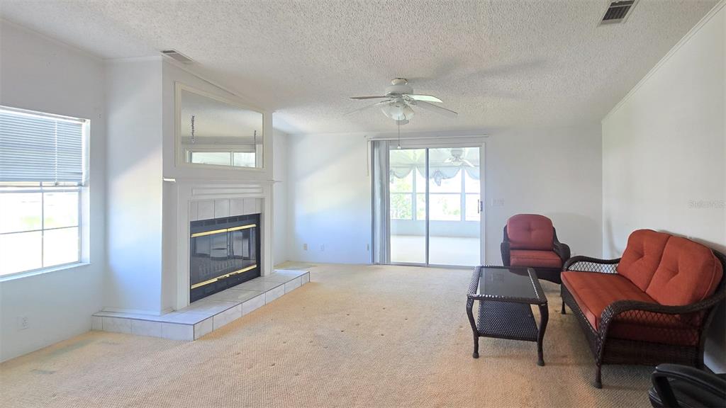 A living room features beige carpeting, a fireplace with a mirror, and sliding glass doors — 300 BEECH COURT, COCOA, FL
