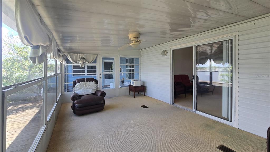 A sunroom with carpeted flooring, a ceiling fan, and a sliding glass door to the interior — 300 BEECH COURT, COCOA, FL