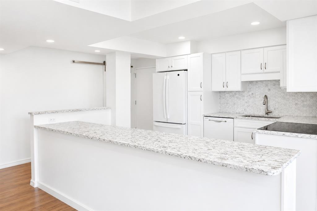 An empty room with wood-look flooring and large windows overlooking palm trees and water — 707 S GULFSTREAM AVENUE UNIT 307, SARASOTA, FL