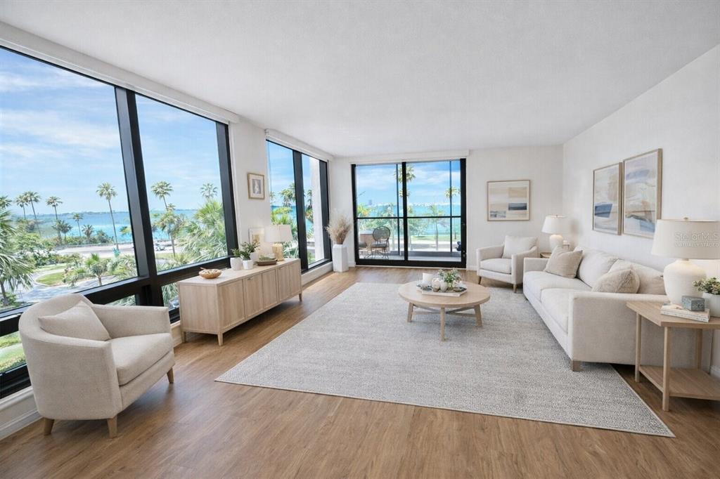 A white kitchen island with marble countertops overlooks a bright living area with ocean views — 707 S GULFSTREAM AVENUE UNIT 307, SARASOTA, FL
