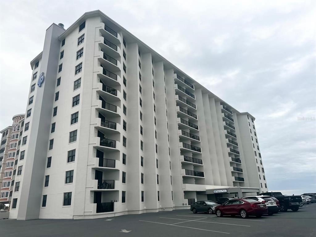 A multi-story white residential building with balconies and a parking lot in front — 1415 OCEAN SHORE BOULEVARD UNIT B060, ORMOND BEACH, FL