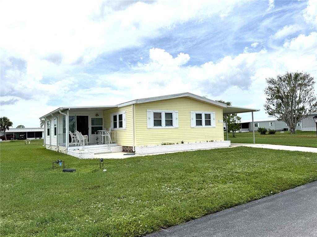 A yellow mobile home with a white brick foundation sits on a grassy lot — 637 LOS ALTOS UNIT 374, NORTH PORT, FL