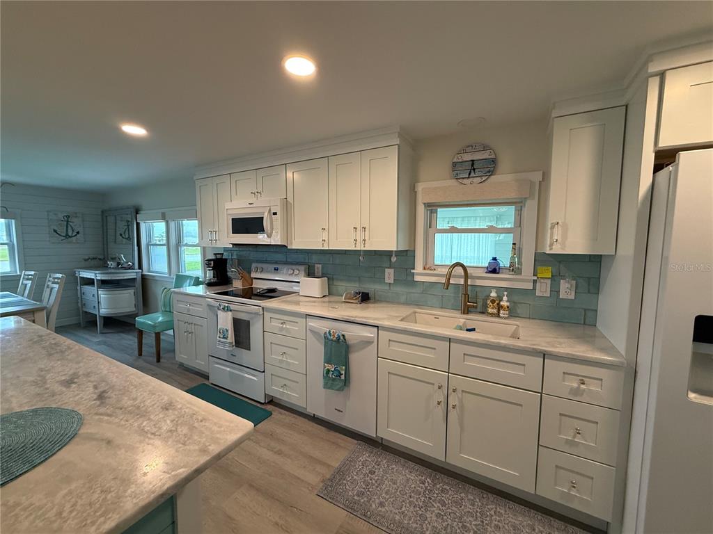 A kitchen features white cabinetry, light countertops, a blue subway tile backsplash, and stainless appliances — 637 LOS ALTOS UNIT 374, NORTH PORT, FL