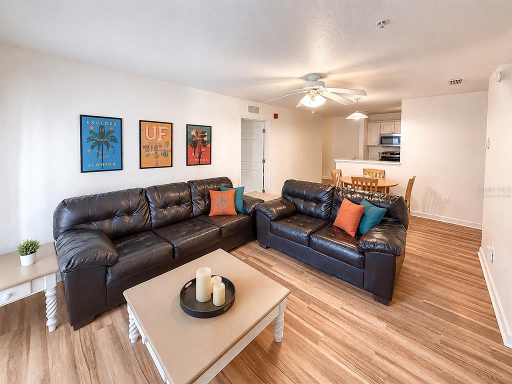 A living room with two dark leather sofas, a coffee table, and an adjacent dining area — 835 SW 9TH STREET UNIT 210, GAINESVILLE, FL