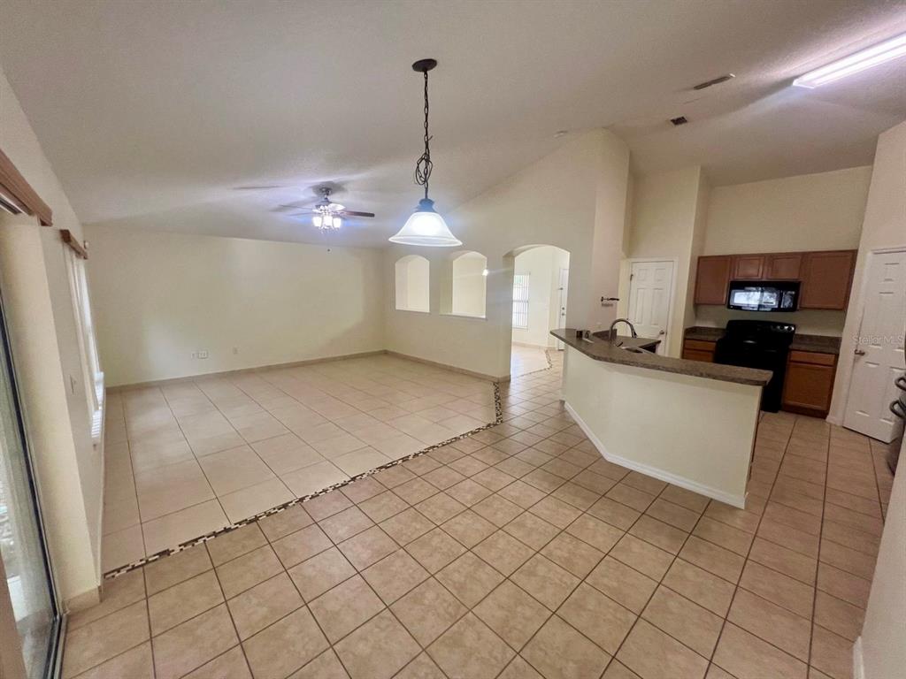 An open-concept living and dining area features tile flooring, a kitchen island, and neutral walls — 3401 HEATH DRIVE, DELTONA, FL