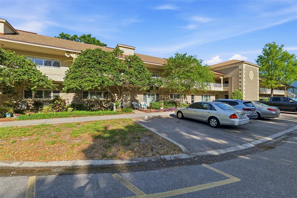 A two-story apartment building with brick siding, a parking lot, and landscaping in front — 2192 SWEDISH DRIVE UNIT 26, CLEARWATER, FL