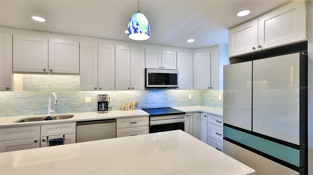 A kitchen with white cabinets, a blue island, and a breakfast bar overlooks a living area — 101 N RIVERSIDE DRIVE UNIT 4120, NEW SMYRNA BEACH, FL