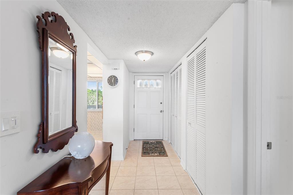 An entryway features a tiled floor, a wooden console table, a mirror, and closet doors — 1776 6TH STREET NW UNIT 409, WINTER HAVEN, FL