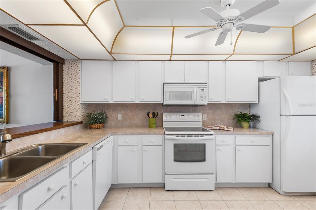 A kitchen with white cabinets, white appliances, a tiled backsplash, and a coffered ceiling — 1776 6TH STREET NW UNIT 409, WINTER HAVEN, FL